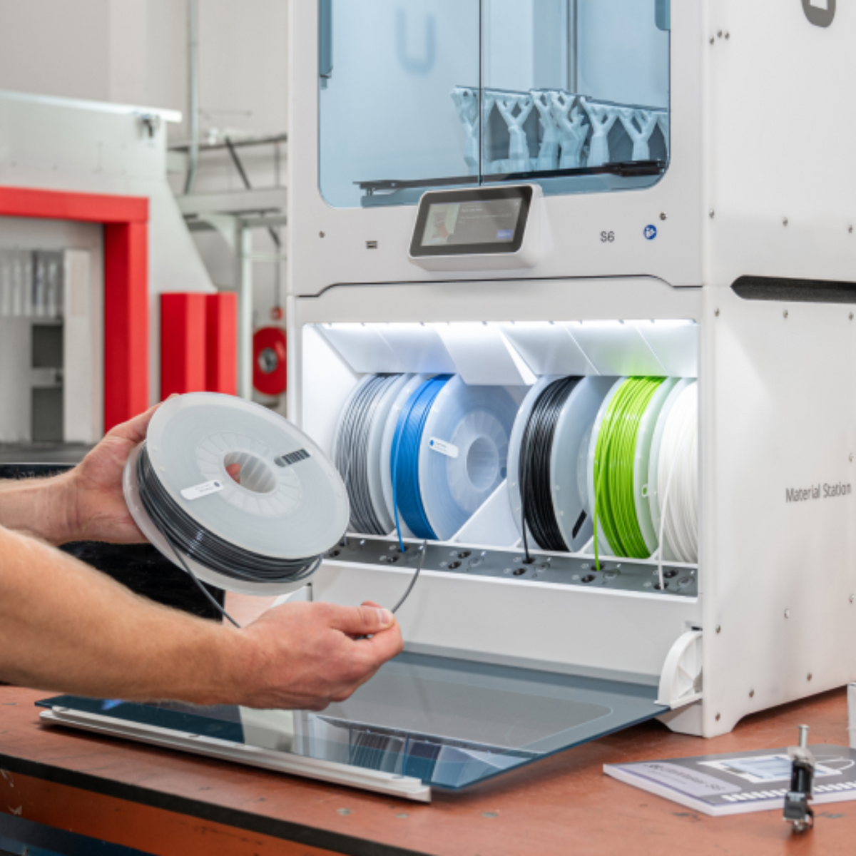 UltiMaker Material Station loaded with six spools beneath an S-series 3D printer